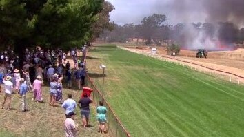 Racegoers look on as firefighters battle the inferno.