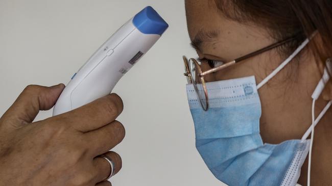 As coronavirus fears grow, security staff check on the temperature of a student entering a university in the Philippines. Picture: Ezra Acayan/Getty