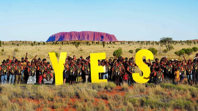 Remote communities in Central Australia posing in front of the iconic Uluru after their council meeting to vote 'Yes' to a Voice to Parliament.