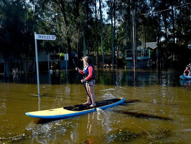 Residents of Geoffrey Road in Chittaway Bay take to the flooded street in water craft. Picture: Jeremy Piper