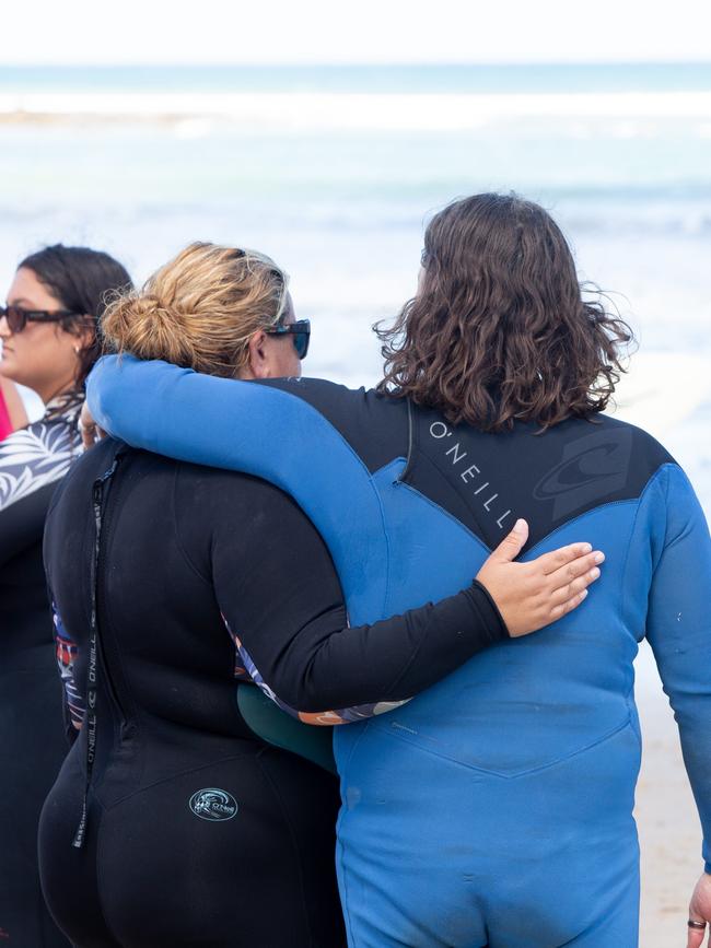 Mourners embrace on the beach. Picture: Brett Hartwig