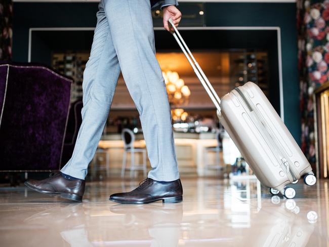 ESCAPE:  Unrecognizable businessman entering or leaving a hotel with luggage. Man walking in the hotel entrance hall. Picture: Istock