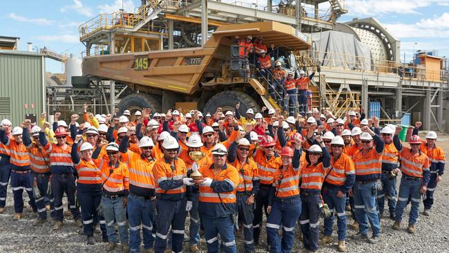 The workers at Evolution Mining's Mount Carlton mine hold the Melbourne Cup made from gold produced by the operation.