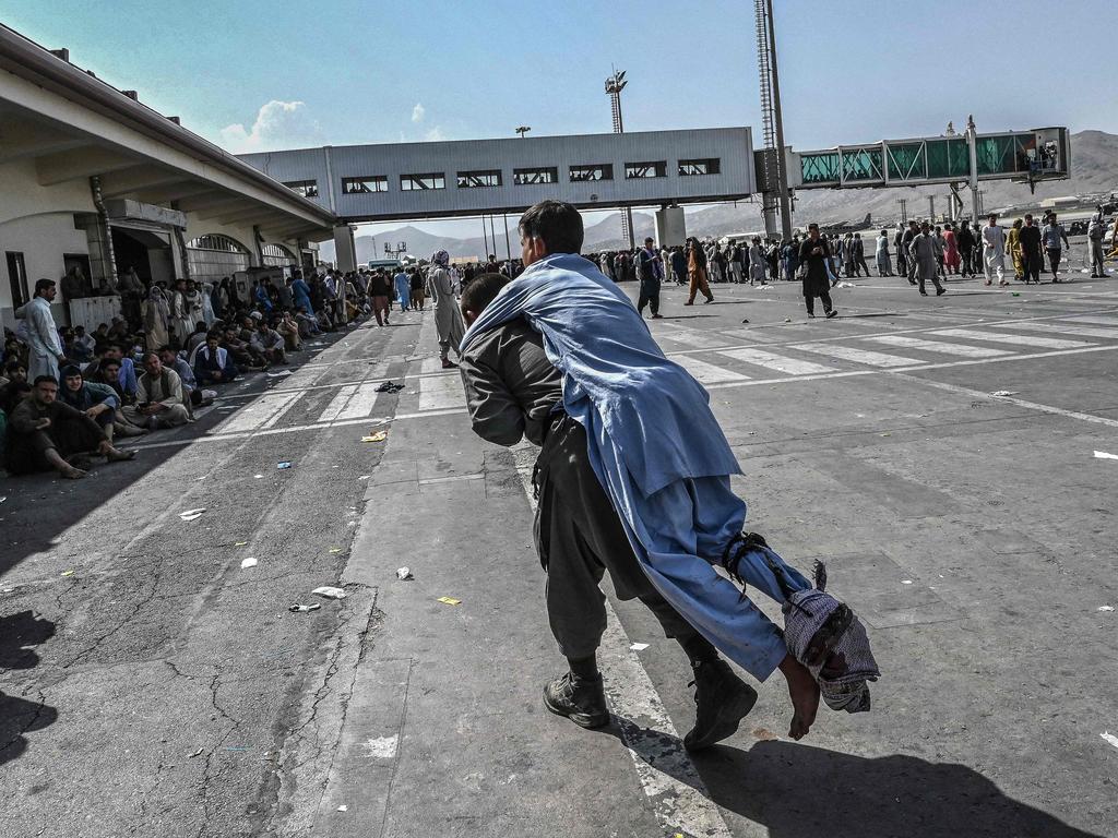 A volunteer carries an injured man on his back towards the airport. Picture: Wakil Kohsar / AFP