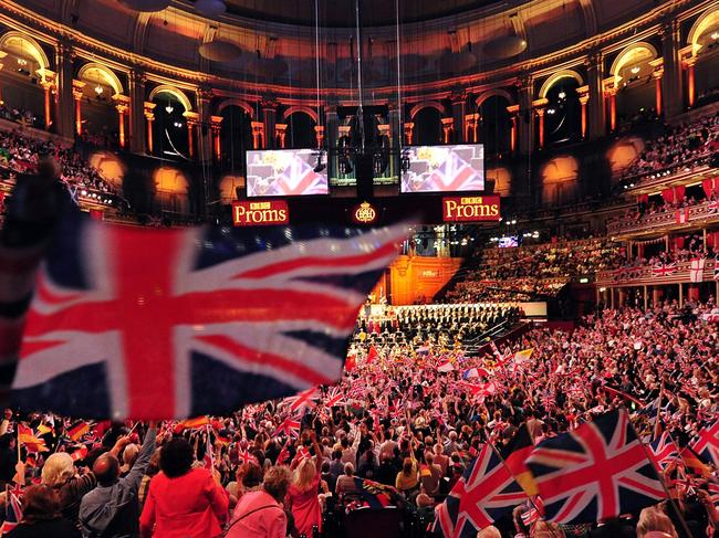 (FILES) In this file photo taken on September 07, 2013 people wave flags at the Royal Albert Hall in west London on the last night of the Proms. - It's a quintessentially British event: thousands of classical music lovers bobbing up and down at the Last Night of the Proms, waving the Union Jack, singing "Rule Britannia!" and "Land of Hope and Glory". (Photo by CARL COURT / AFP)