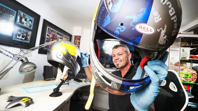 Antman Helmet Design owner Anthony Wolski pictured holding V8 Supercar driver Shane Van Gisbergen’s helmet while he works on Jamie Whincup’s. Picture: Nigel Hallett