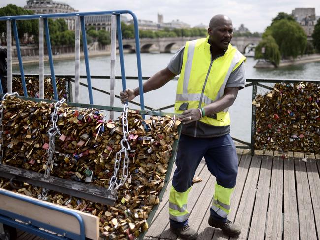 Removal ... a worker drags away a railing with thousands of lovelocks attached to it. Picture: AFP/Stephane De Sakutin
