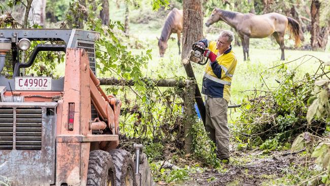 Tony Duncan, who witnessed a woman caught in floodwaters, fixes fencing after flooding through Springacre Road in Thornlands. Picture: Richard Walker.