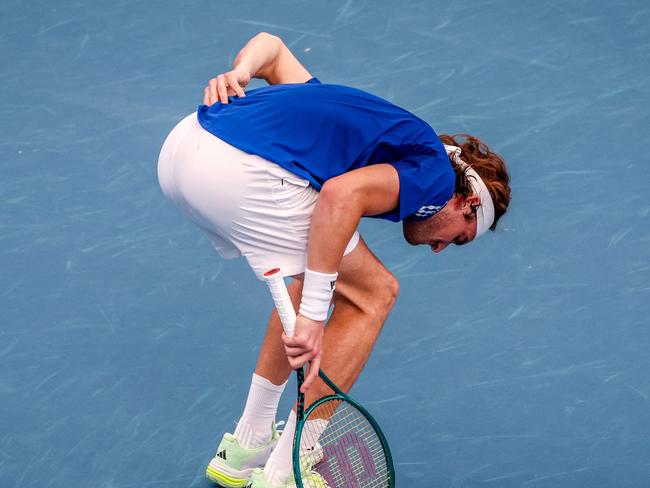 Greece's Stefanos Tsitsipas grabs at his back.