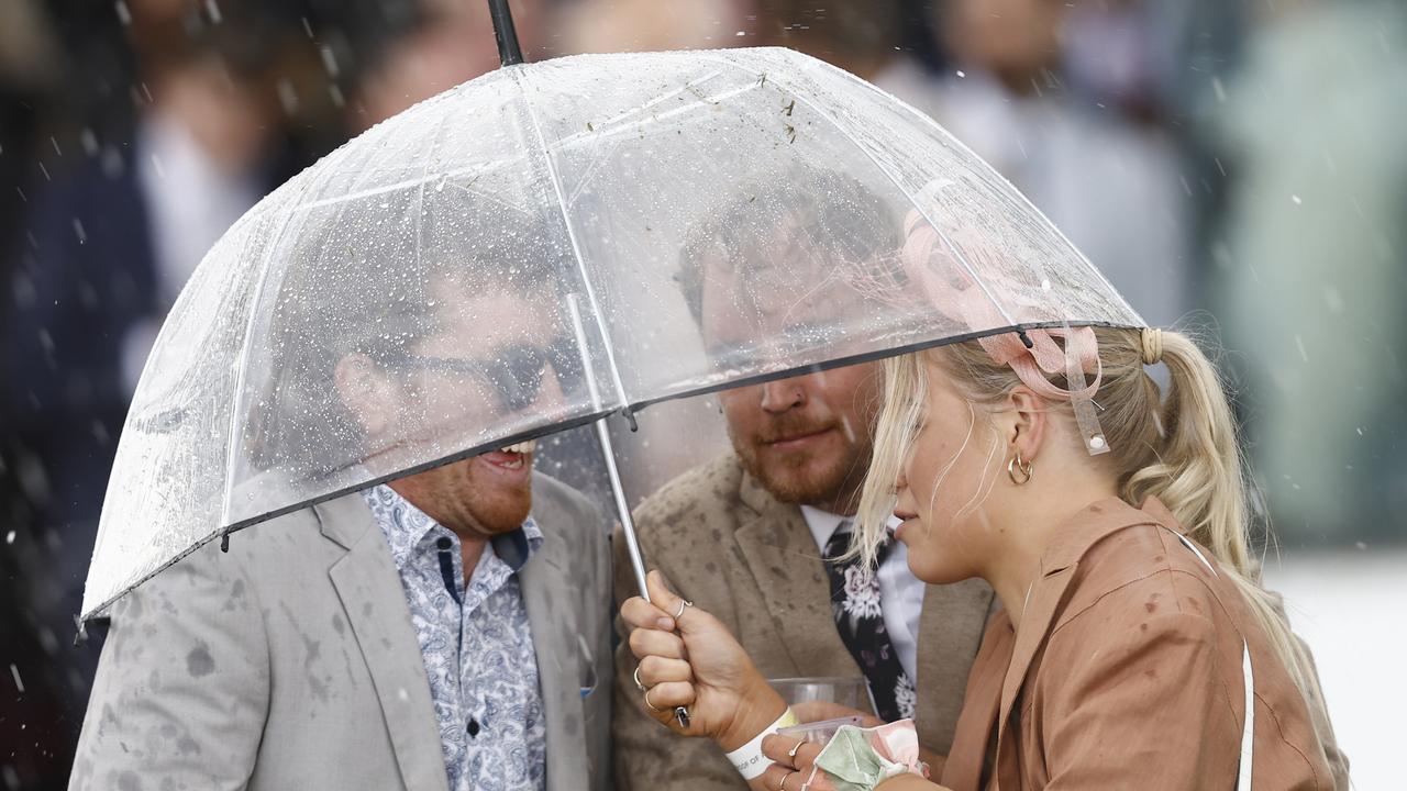Racegoers take cover as hail and rain hit Flemington on Melbourne Cup Day at Flemington in 2022. Picture: Darrian Traynor / Getty Images