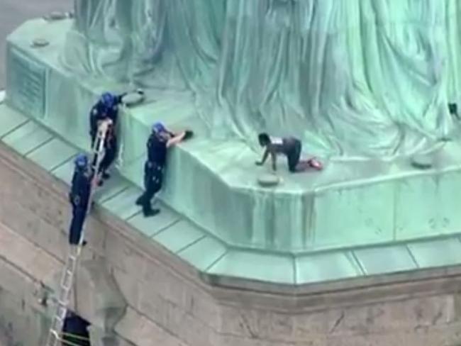 This still image taken from video Courtesy of PIX11 News in New York, shows police talking to a woman who climbed to the base of the Statue of Liberty in New York on July 4, 2018.  According to media reports, Liberty Island has been evacuated and ferries to the site have been halted, while law enforcement attempt to get the woman down from the statue.  / AFP PHOTO / PIX11 News / HO / RESTRICTED TO EDITORIAL USE - MANDATORY CREDIT "AFP PHOTO / Courtesy of PIX11 News" - NO MARKETING NO ADVERTISING CAMPAIGNS - DISTRIBUTED AS A SERVICE TO CLIENTS