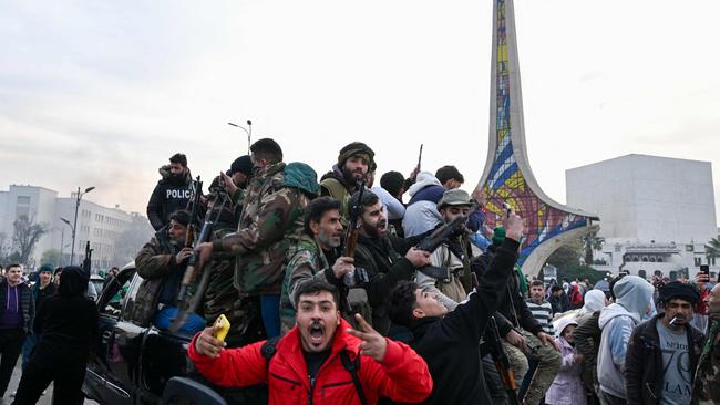 People celebrate next to anti-government fightres at Umayyad Square. Picture: Louai Beshara/AFP