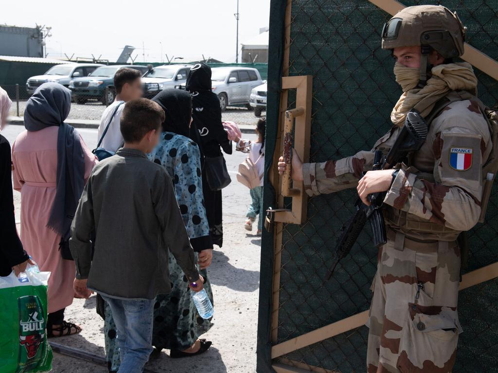 A French soldier watches on as people walk to board a military flight at Kabul airport. picture: AFP