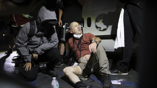 Protesters help news photographer Nick Stern after he was shot by a “sponge bullet”. Picture: AP Photo/Ethan Swope