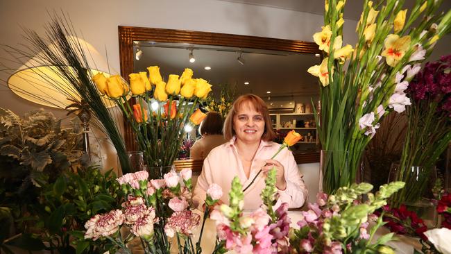 Main Beach Business and Tourism Association Incorporated president Margot de Groot among the flowers decorating her shop. Picture: Jason O'Brien