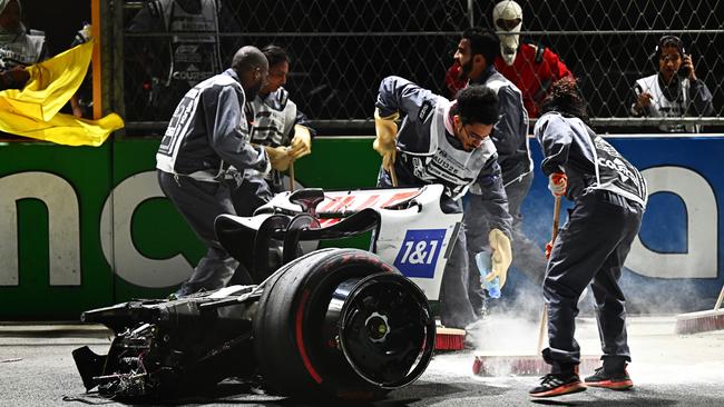 Track marshals clean debris from the track following the crash of Mick Schumacher