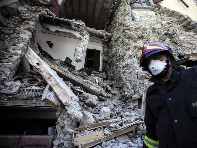 A firefighter walks past a collapsed house in Arquata, central Italy, Thursday, Aug. 25, 2016 where a 6.1 earthquake struck just after 3:30 a.m., Wednesday. Rescue crews raced against time Thursday looking for survivors from the earthquake that leveled three towns in central Italy, but the death toll rose to 241 and Italy once again anguished over how to secure its towns and cities, new and old, built on seismic lands. (Angelo Carconi/ANSA via AP)