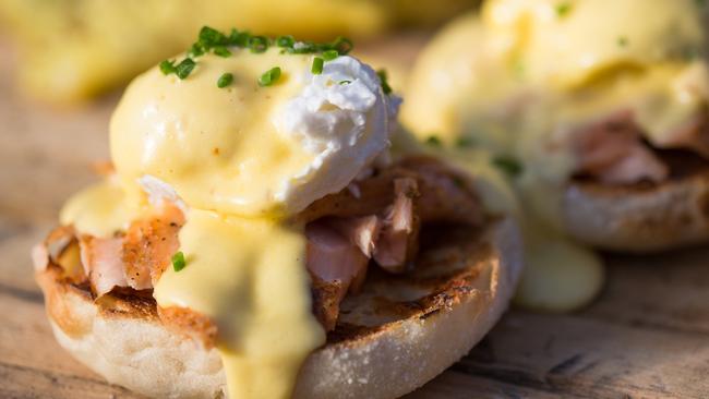 A horizontal composition of a variation of the typical eggs benedict in which bacon is replaced by trout or salmon, served with the usual poached egg and hollandaise sauce, all served on a toasted English muffin.