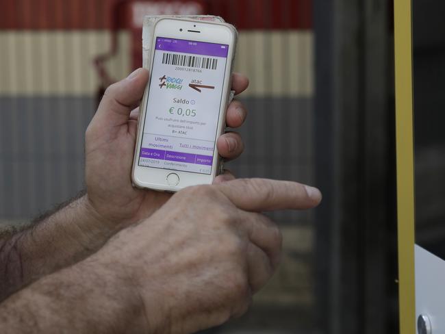 A man holds his mobile phone bearing an application showing the credit earned after inserting a plastic bottle into an automatic recycling bin outside a subway station in Rome, Wednesday, July 24, 2019. Rome unveiled Tuesday three test machines around metro stations where passengers can drop plastic water bottles, receiving five cents apiece, which goes to the passengerâ€™s account in partner apps to be redeemed for public transportation tickets. (AP Photo/Gregorio Borgia)