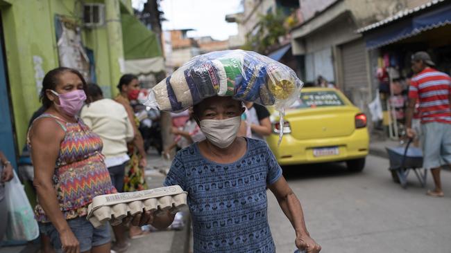 Maria Rita Dias dos Santos, wearing a protective face mask, carries food to her home in Rio de Janeiro. Picture: AP