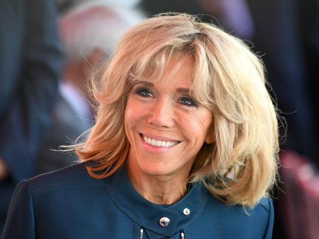 (FILES) This file photo taken on July 14, 2017 shows Brigitte Macron (C), wife of French President, smiling ahead of the start of the annual Bastille Day military parade on the Champs-Elysees avenue in Paris.  French President Emmanuel Macron is preparing to backpedal on the issue of creating an official First Lady position for his wife amid attacks from left-wing opponents and a petition against the move, officials and reports said on August 7, 2017.  / AFP PHOTO / ALAIN JOCARD