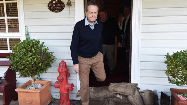 Opposition Leader Bill Shorten steps over sandbags while visiting the flood-hit Tasmanian town of Forth. Picture: Mick Tsikas/AAP