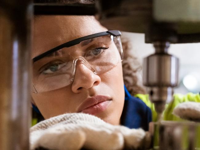 TRADESWOMAN/ TRADE WOMAN/ TRADESMAN/ TRADIE/BUILDING INDUSTRY: Close-up of female apprentice using yoke machine. Female engineer is wearing protective glasses in factory. She is working in manufacturing industry.