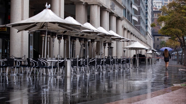 A woman walks past an empty dining area in Sydney during COVID-19 lockdown. Picture:  Getty Images