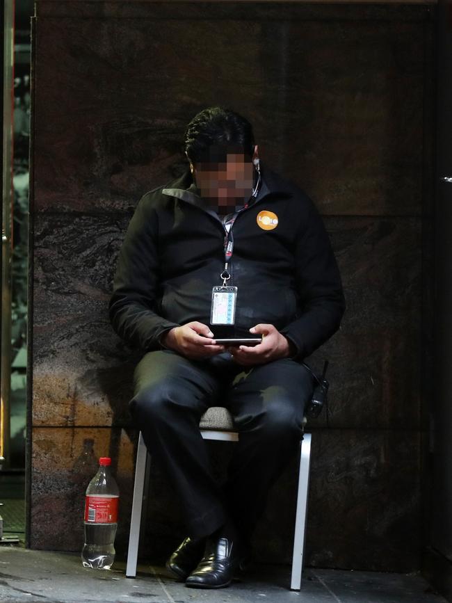 A security guard watching a video on his phone outside the Adina Apartment Hotel Sydney Town Hall. Picture: Jonathan Ng