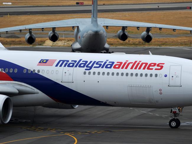 PERTH, AUSTRALIA - MARCH 25:  A Malaysia Airlines plane prepares to go out onto the runway and passes by a stationary Chinese Ilyushin 76 aircraft (top) at Perth International Airport on March 25, 2014 in Perth Australia.  The Australian Maritime Safety Authority has suspended the air and sea search for the missing Malaysian Airlines flight MH370 due to poor weather conditions in the search area. Search operations are expected to resume tomorrow.  (Photo by Greg Wood - Pool/Getty Images)