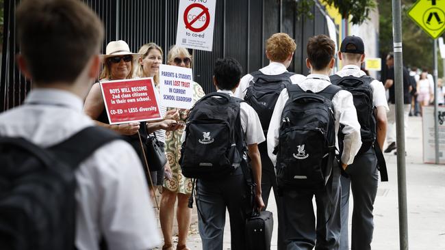 Students walk past protesters on the first day of school. Picture: Richard Dobson