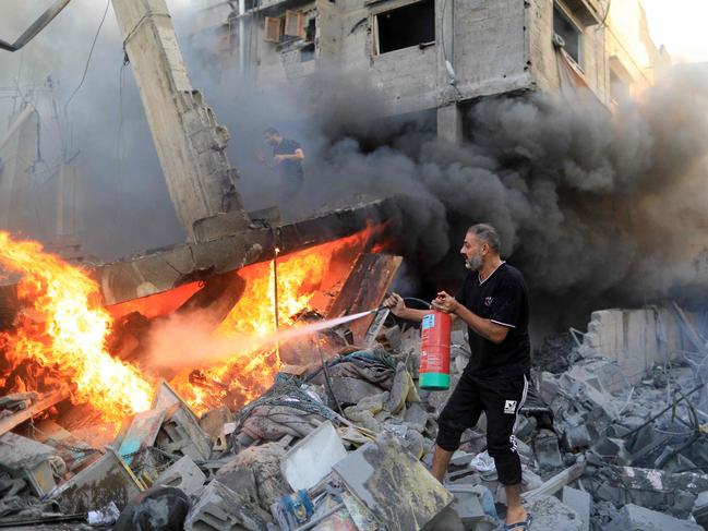 A Palestinian man uses a fire extinguisher to douse a fire following an Israeli strike in Khan Yunis. Picture: Yasser Qudih/AFP