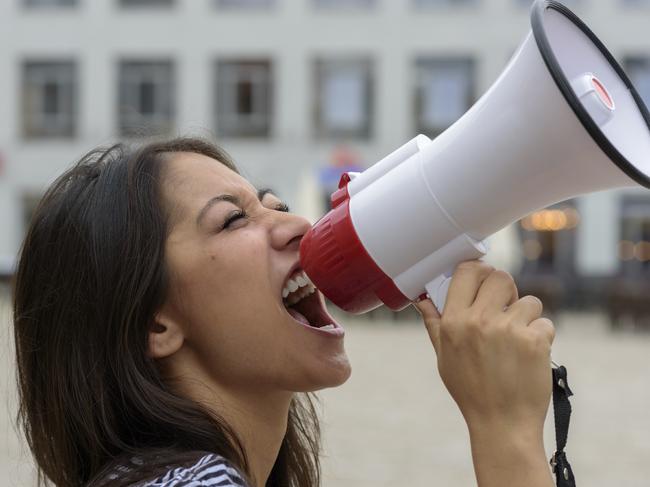 Woman yelling into a bullhorn on an urban street voicing her displaeasure during a protest or demonstration, close up side view of her face. Picture: iStock to go with question: Should I include my involvement with political and activist groups on my resume?