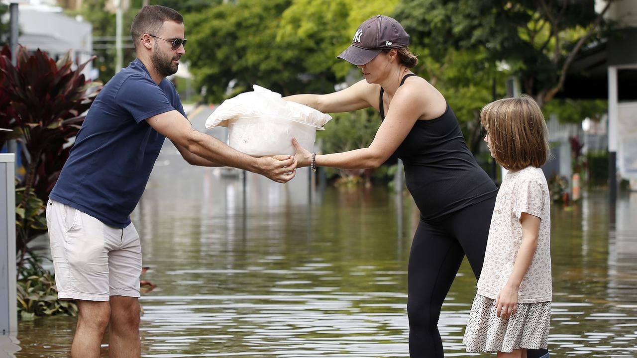 People pictured moving product out of shops in the flood waters at Rosalie after the heavy rain storms passed through Brisbane. (Image/Josh Woning)