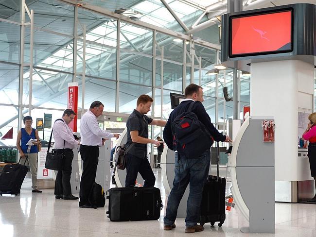 Qantas customers check themselves in at Sydney domestic airport after the airline said it would freeze growth at Jetstar after major losses. 