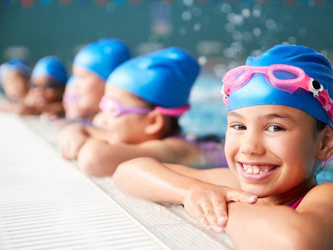 Portrait Of Children In Water At Edge Of Pool Waiting For Swimming Lesson