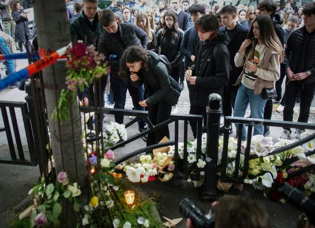 People continued to place flowers, toys and light candles at makeshift memorial on the pavement outside of the school