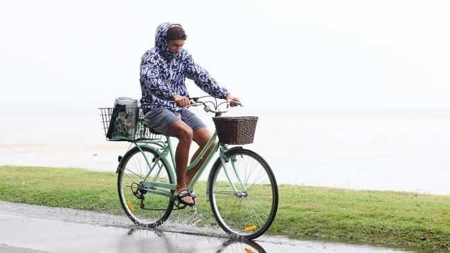 The wet season continues to persist in Far North Queensland, with rainy weather forecast to continue for the remainder of the week. Landscape gardener Clement Hug does his best to protect himself from the rain as he rides his bike through puddles on the Cairns Esplanade on his day off. Picture: Brendan Radke