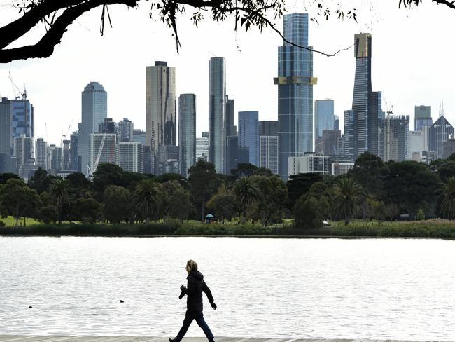 MELBOURNE, AUSTRALIA - NewsWire Photos June 02, 2022: A woman walks around Albert Park Lake with the Melbourne skyline in the background on a day when the city temperature is not expected to go above 12'. Picture: NCA NewsWire / Andrew Henshaw