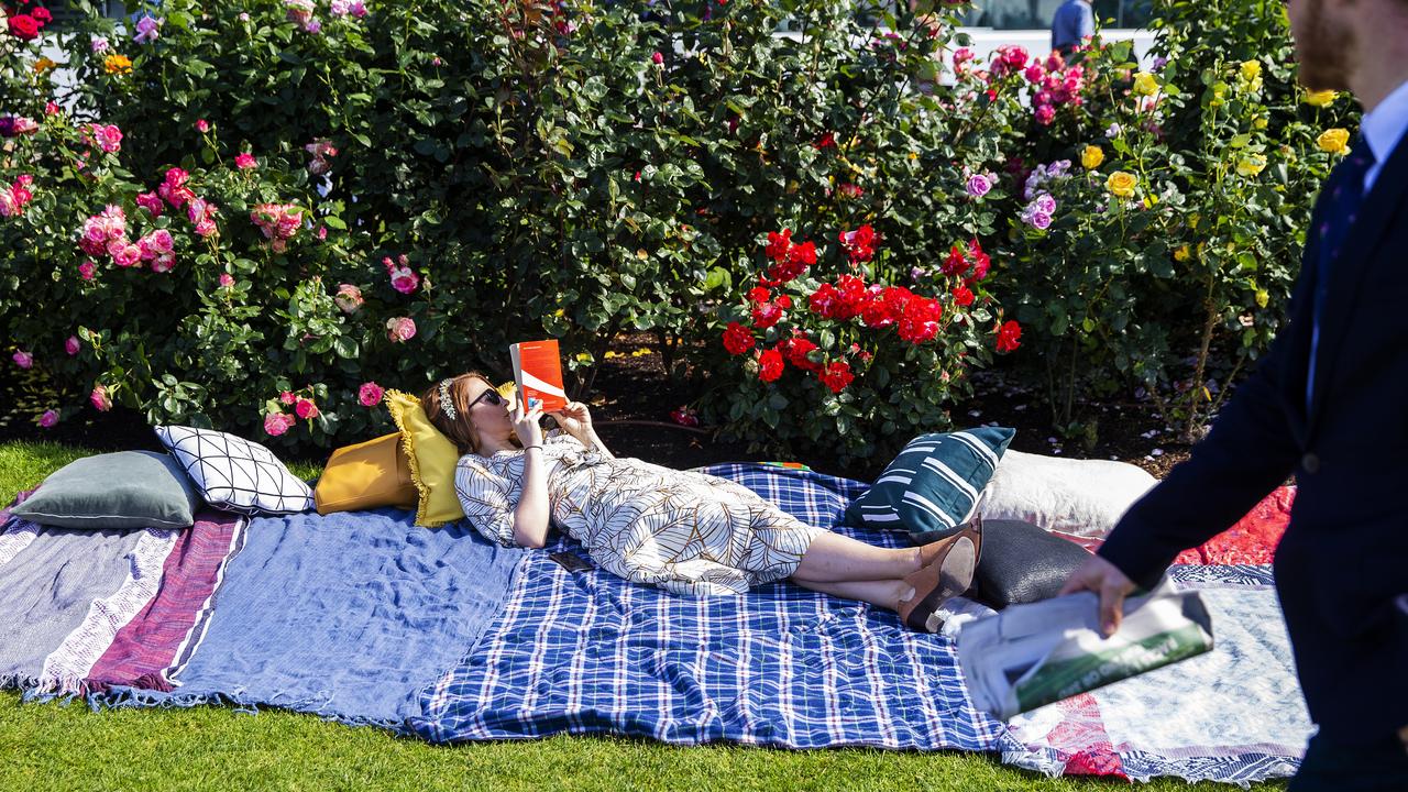 A racegoer lays on a blanket reading a book. Picture: Getty Images