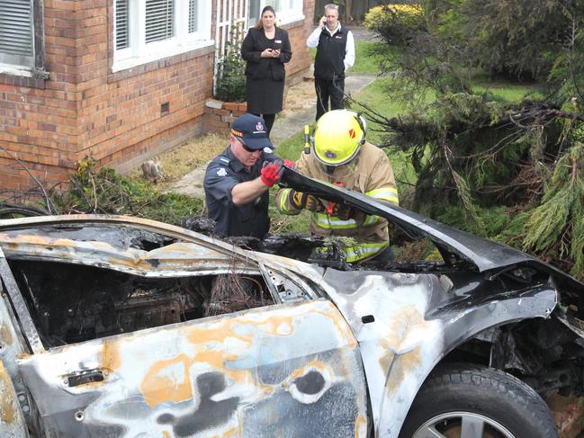 Authorities examining a car which caught fire after ploughing through a fence in the Launceston suburb of Newnham early today. Picture: BRUCE MOUNSTER