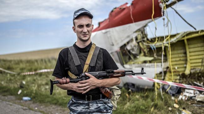 An armed pro-Russian separatist stands guard near a piece of the downed plane. Picture: AFP