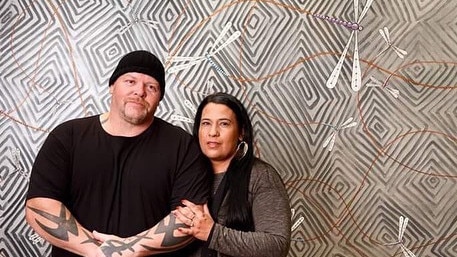 Artists Robby Wirramanda-Knight (left) and Jackie Wirramanda (right), standing in front of a painting by Mr Wirramanda-Knight. Picture: Instagram.