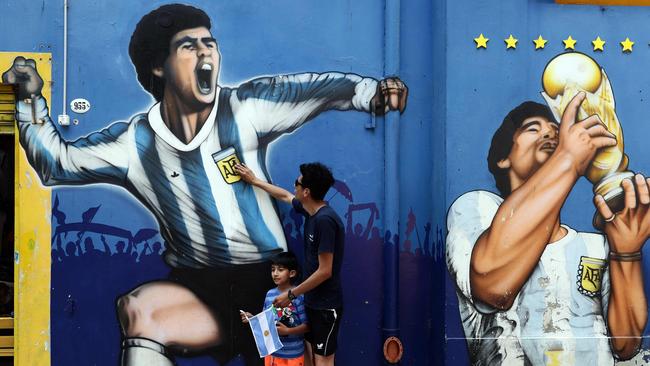 A man and his child pay tribute next to a mural depicting Argentine football legend Diego Maradona in Buenos Aires Picture:AFP