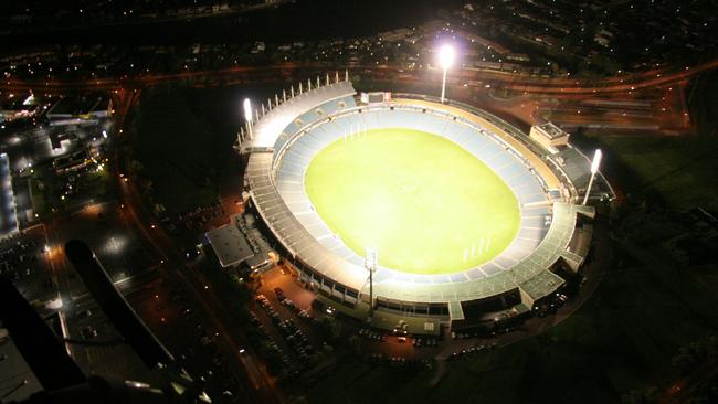 Aerial view of AAMI Stadium at night with the lights on.