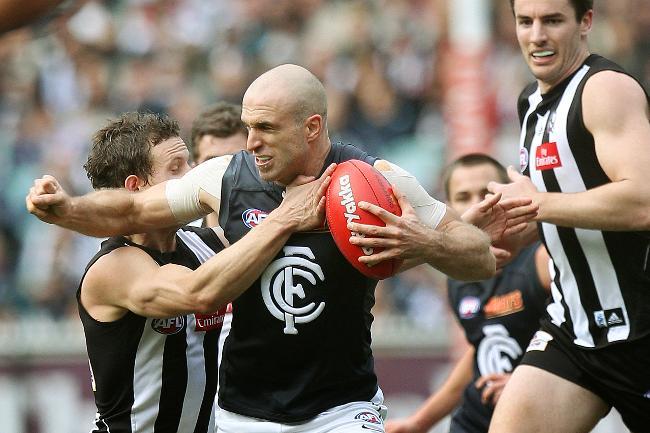 Chris Judd tries to break a tackle against Collingwood.