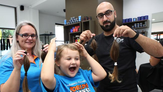 Kylie Pamment, Jel’z Barber Shop owner Michael Nagi and Cooper after the ponytails were cut off. Picture: Rob Pozo