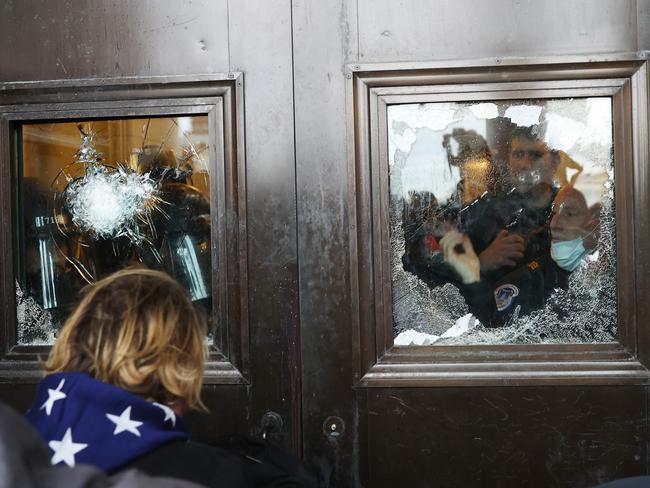 A Capitol police officer looks out of a broken window as protesters gather on the US Capitol Building. Picture: AFP