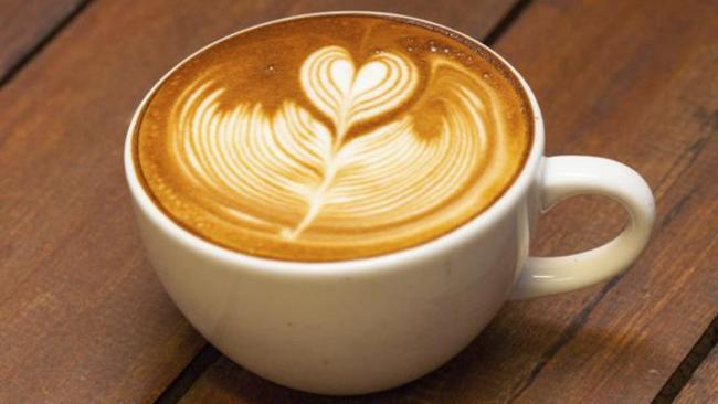 Latte art, coffee on the wooden desk as background.