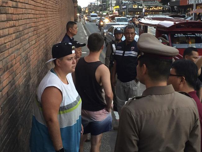 In this Thursday, Oct. 18, 2018, photo, Canadian Brittney Lorretta Katherine Schneider, left, and British Furlong Lee, second left, stand in front of Tha Pae Gate in Chiang Mai province, northern Bangkok, Thailand. They face up to 10 years in prison on charges of spraying paint on an ancient wall in northern Thailand, police said Friday. (Chiang Mai News via AP)